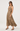 A woman modeling a sleeveless leopard-print maxi dress with a halter-style neckline, shown against a plain light gray studio background.