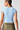 Person wearing a light blue athletic top and green shorts on a plain background