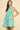 Woman wearing a sleeveless dress with a leaf pattern on a beige background