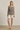 Woman wearing a checkered top and white shorts on a plain background