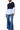 A model wearing a color-block knit and shirt blouse with blue bell sleeves and wide-leg blue jeans, photographed against a plain white studio background.