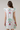 Woman wearing a white dress with floral embroidery on a plain background