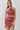 A woman modeling a two-piece halter crop top and matching high-waisted mini skirt set in a dusty rose pink paisley pattern, set against a plain light gray studio background.