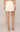 A model from the back wearing a cream-colored mini skirt with floral lace embroidery along the hem, paired with beige lace-up heeled sandals against a neutral studio background.