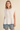 Woman wearing a white sleeveless top and denim shorts on a beige background