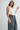 Woman wearing a white top and denim skirt against a plain background