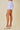 Person wearing a light purple plaid skirt on a beige background