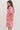 Woman wearing a pink outfit with floral patterns on a plain background
