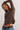 Woman wearing a brown ribbed sweater and blue jeans against a white background