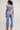 A woman shown from the back wearing a light blue sleeveless crop top and matching high-waisted jogger pants, paired with beige slip-on shoes, against a plain light gray studio background.