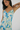 Woman wearing a floral slip dress with blue flowers on a plain background