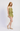 A woman modeling a light green ruffled romper with a subtle floral pattern, paired with beige woven flat shoes, against a plain light gray studio background.