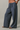 A person wearing loose, wide-leg pants with horizontal navy and white stripes, shown from the waist down against a plain light gray studio background.