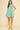 Woman wearing a green leaf-patterned dress on a beige background
