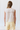 Person wearing a white sleeveless top with lace details and light yellow shorts on a white background