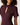 A close-up of a woman wearing a short-sleeve mock neck dress in a deep plum purple color, featuring a keyhole cutout on the chest.