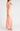 Woman wearing a long, light pink dress against a white background