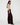 A woman modeling a pair of wide-leg burgundy velvet pants, paired with a white sleeveless crop top and black pointed-toe flats, standing against a plain white studio background.