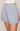 Light blue shorts worn by a person on a beige background