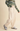 A person wearing cream wide-leg pants with a drawstring waist, paired with a green patterned sweater and gray sneakers, standing against a plain beige studio background.