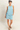 Woman wearing a light blue sleeveless top and shorts on a plain background