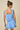 Woman wearing a light blue dress with floral cutouts on a beige background