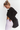 A woman in a black sheer long-sleeve crop top and white leggings stands against a plain white background, holding a black tote bag.