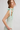Woman wearing a light green dress with a bow detail on a plain background