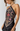 A woman wearing a black halter-neck dress with a large floral print in pink, red, and gold on the front panel, photographed against a light gray studio background.
