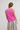 Person wearing a pink sleeveless top and colorful striped pants on a plain background