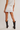Person wearing a white skirt and black boots on a plain background