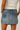 Denim skirt worn by a person on a plain background