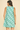 Woman wearing a sleeveless dress with a leaf pattern on a beige background