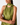 A close-up of a model wearing a green satin halter dress with a white polka dot pattern. The dress features a keyhole cutout at the neck and a draped, asymmetrical neckline.