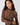 A woman wearing a brown sheer long-sleeve mock neck top with a beige and white spotted animal print, paired with gold hoop earrings, against a light gray background.