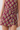 A close-up of a person wearing a sleeveless top and matching shorts set in a deep burgundy fabric with a colorful floral print in yellow, blue, and green.
