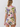 A woman shown from the back wearing a short-sleeve ruffled top and matching ruffled shorts set in a cream base with a colorful tropical floral print.