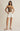 Woman wearing a brown strapless top and white shorts on a beige background
