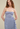 Woman wearing a light blue dress with thin straps on a beige background