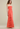 Woman wearing a coral strapless gown with ruffled layers on a beige background