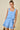 Woman wearing a light blue dress with floral cutouts on a beige background