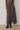A high-waisted, long pleated skirt with a brown, gray, and white plaid pattern, styled with a brown ribbed knit top and dark brown boots.