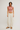 Woman wearing a pink crop top and beige pants on a white background