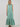 A sleeveless collared maxi dress with vertical green, blue, and white stripes, featuring a button-front placket and a ruffled hem, modeled against a plain light gray studio background.