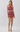 A woman modeling a two-piece halter crop top and high-waisted mini skirt set in a dusty rose pink paisley pattern, paired with clear strap high-heeled sandals, against a light gray studio background.