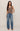 Woman wearing a brown sleeveless top and blue jeans on a beige background