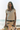 Woman standing on a beach wearing a white top and pants with dragonfly designs.