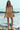 Woman in a striped dress standing on a rocky beach with ocean in the background