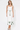 Woman wearing a white dress with green floral embroidery on a white background