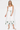 Woman wearing a white dress with green floral patterns on a white background